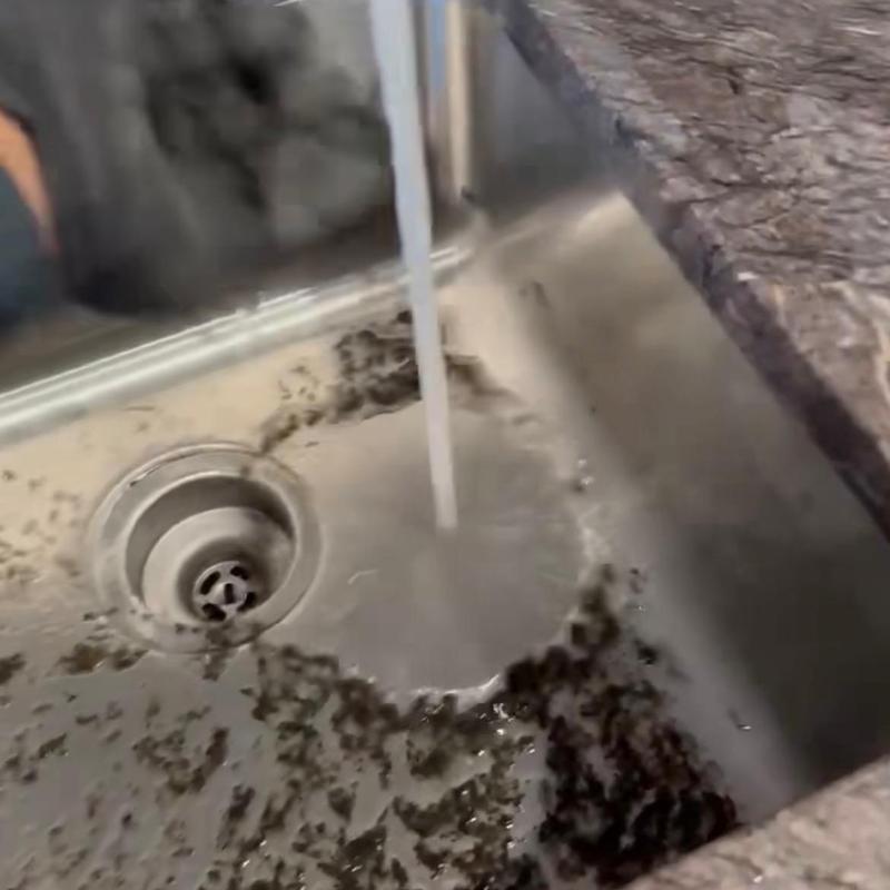 Kitchen sink drain with running water and debris buildup