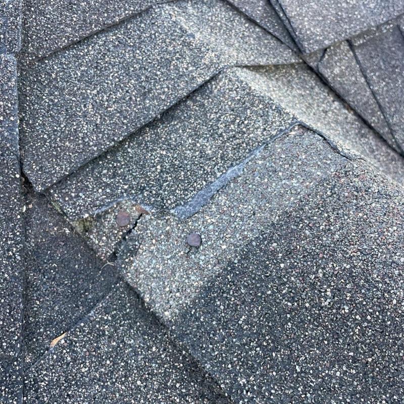 Asphalt shingles with exposed nails and cracks