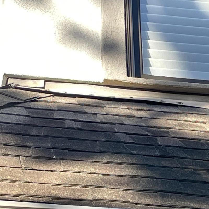 Asphalt shingles with lifted corners near window flashing