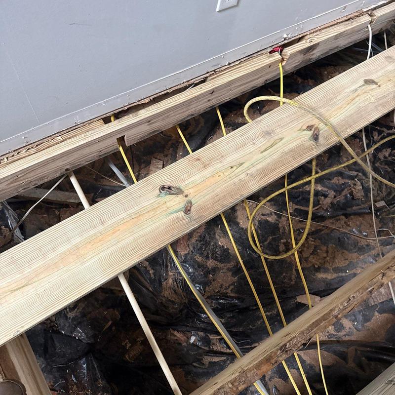 Floor joists exposed with electrical wiring beneath floorboards