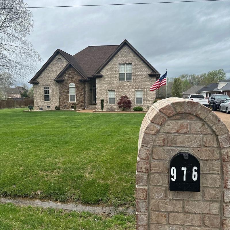 Brick mailbox with house number 976 near brick home