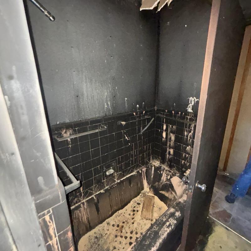 Bathtub and tile fire damage in blackened bathroom
