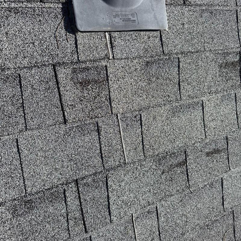 Asphalt shingles with hail damage near roof vent