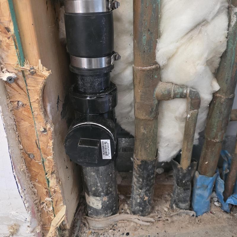 Split ABS clean-out installation with copper pipes nearby