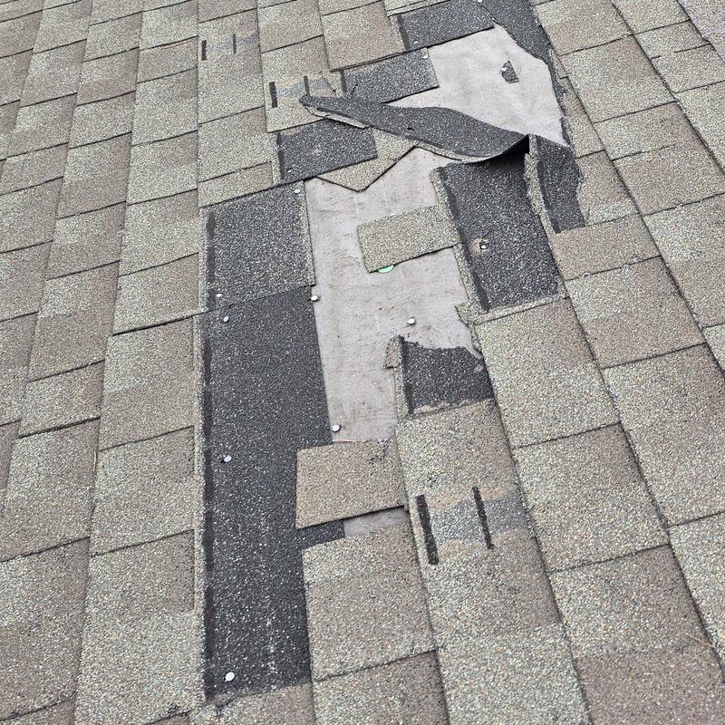 Asphalt roof shingles damaged and missing sections