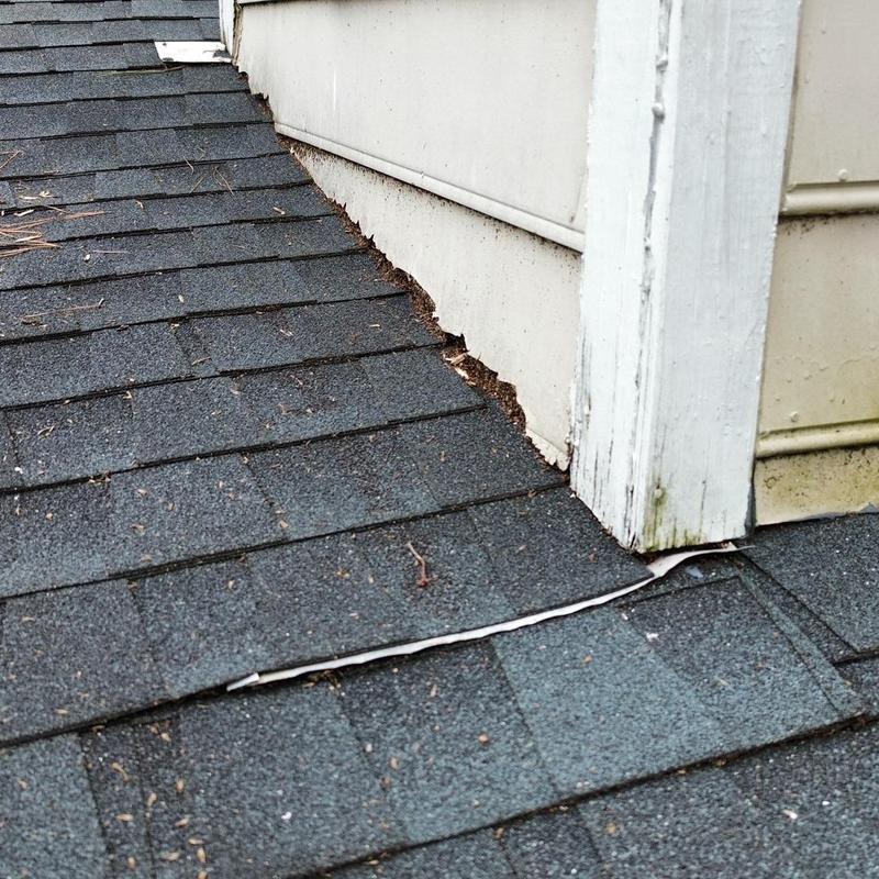 Chimney flashing with damaged roof shingles and trim
