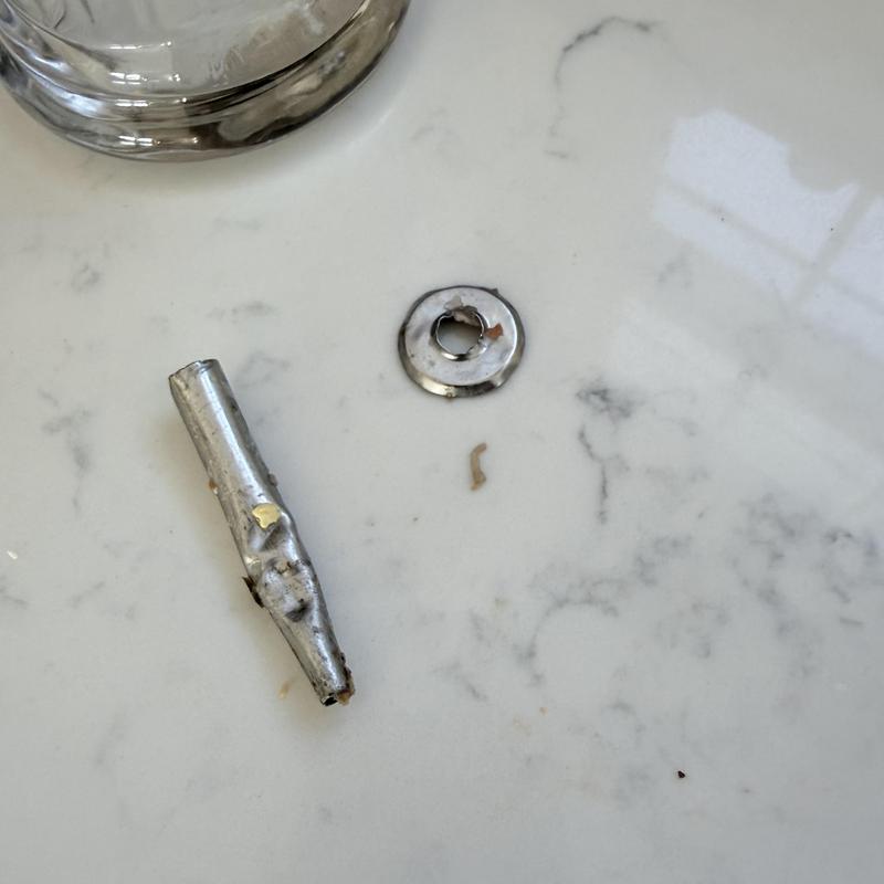 Disposal jammed metal fragment on countertop near glass