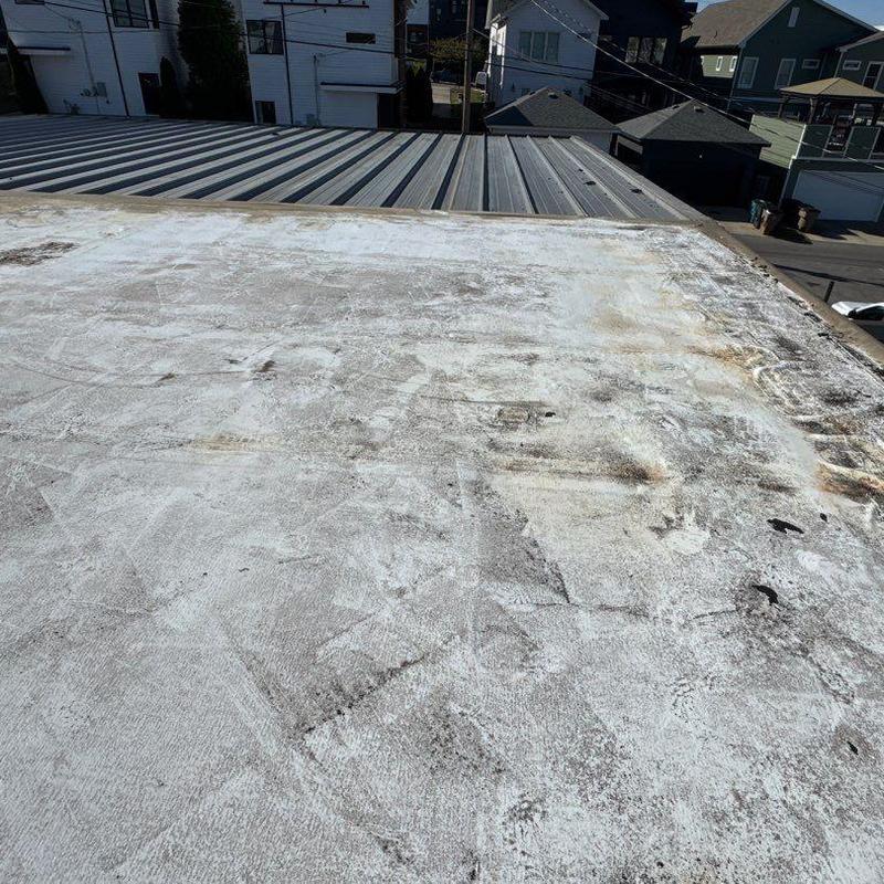 TPO flat roof with wear and discoloration near metal roof