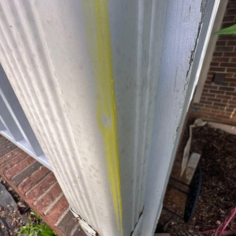 Wooden column with yellow paint streak and minor damage