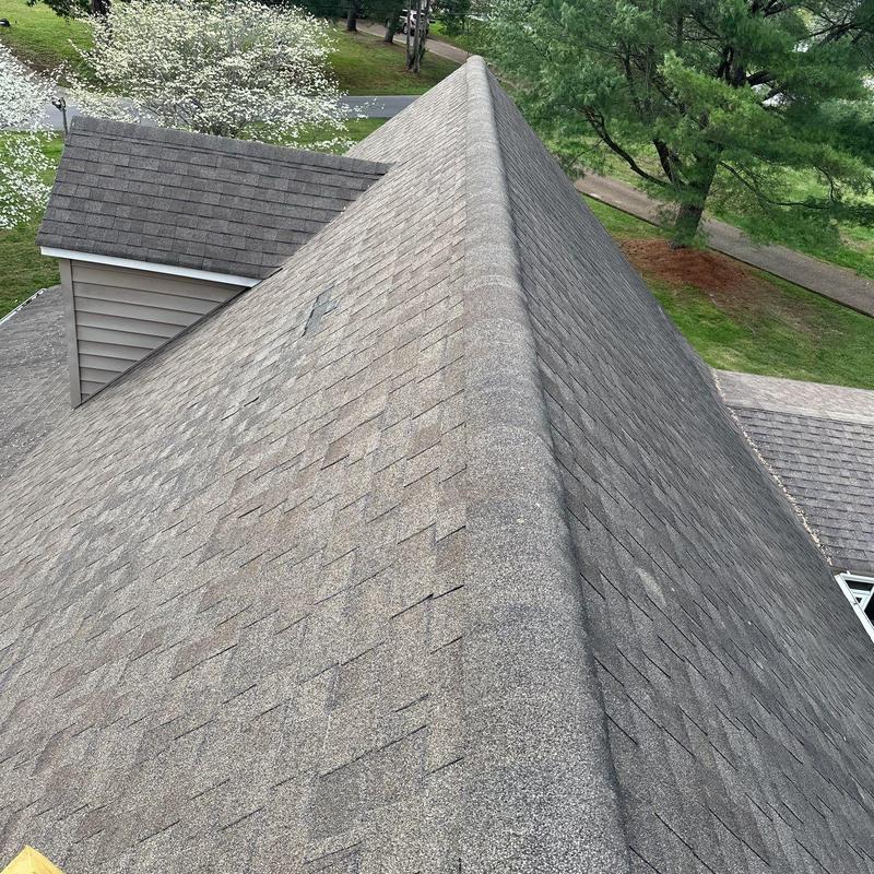 Asphalt shingle roof ridge with visible hail damage
