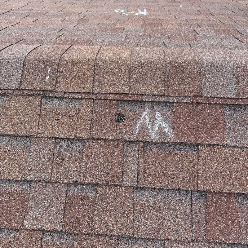 Asphalt shingles with hail damage marked for inspection