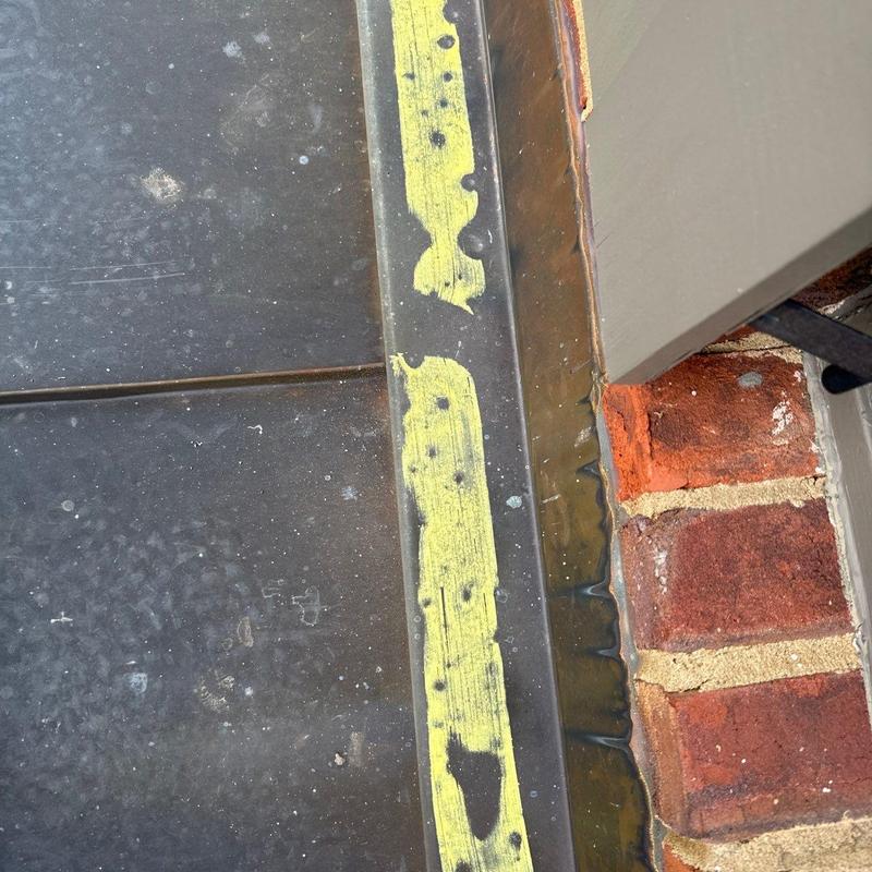 Metal flashing with sealant deterioration by brick wall