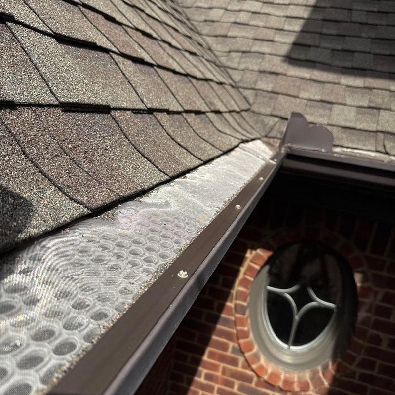Roof shingles and gutter guard near oval window