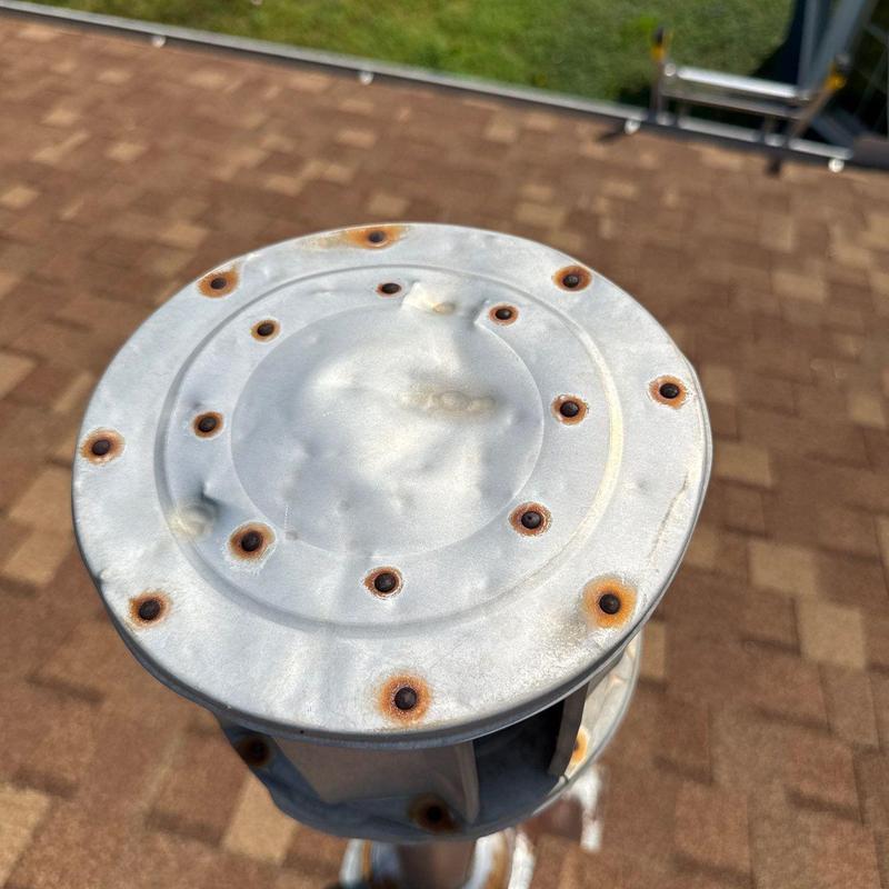 Metal vent cap with rusted and damaged screws on roof