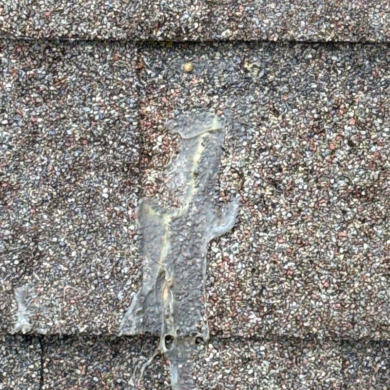 Asphalt shingle with hail damage and sealing material