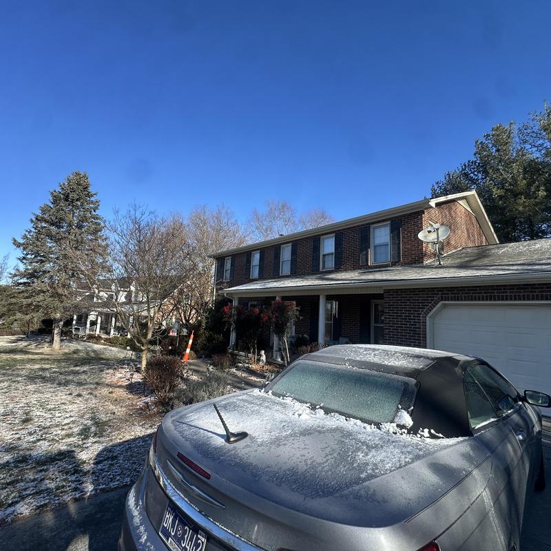 Metal roof on residential home with frost and car