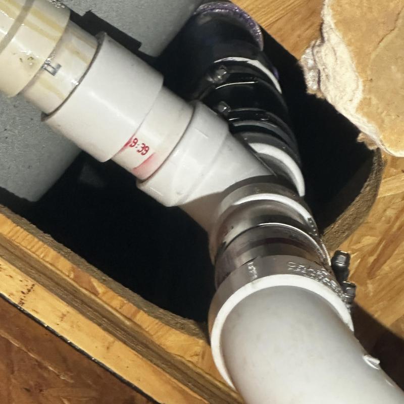 Tub drainage pipe with metal clamps under floorboards