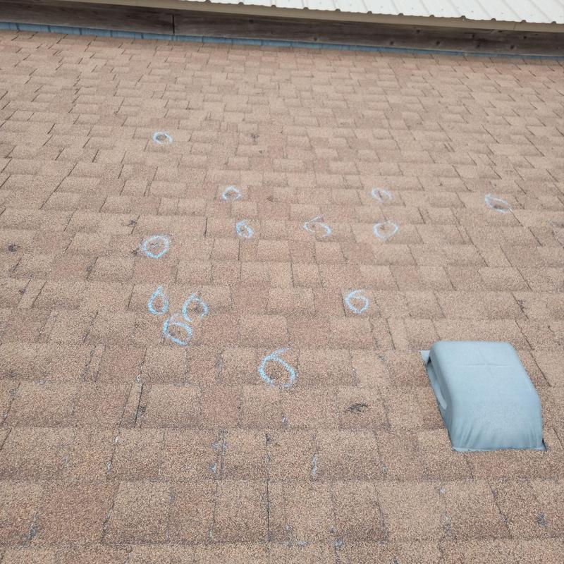 Asphalt shingle roof with hail damage marked in chalk Asphalt shingle roof with hail damage marked in chalk