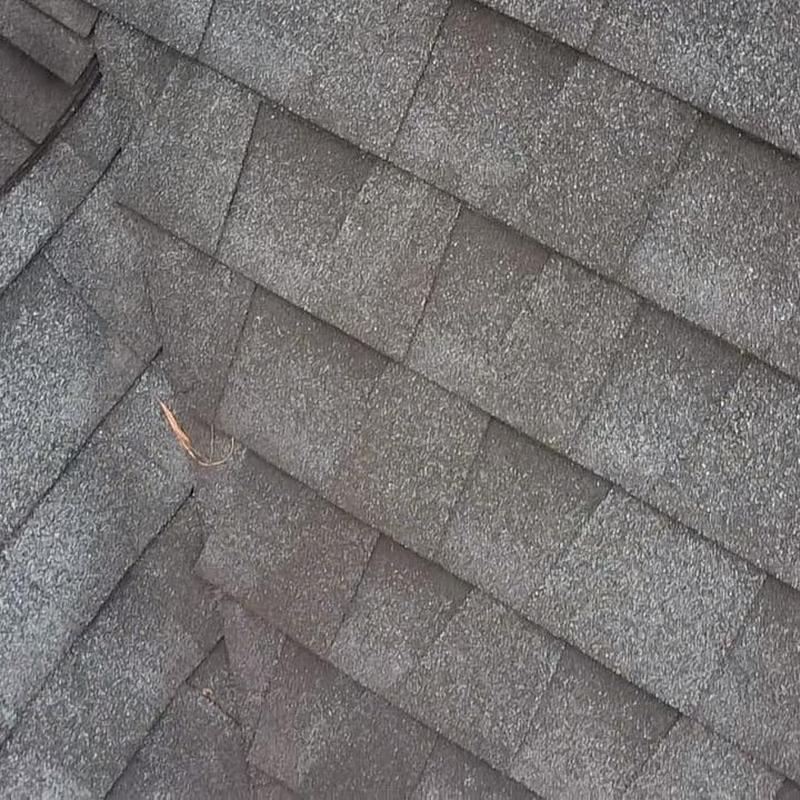 Asphalt roof shingles close-up with debris near seam