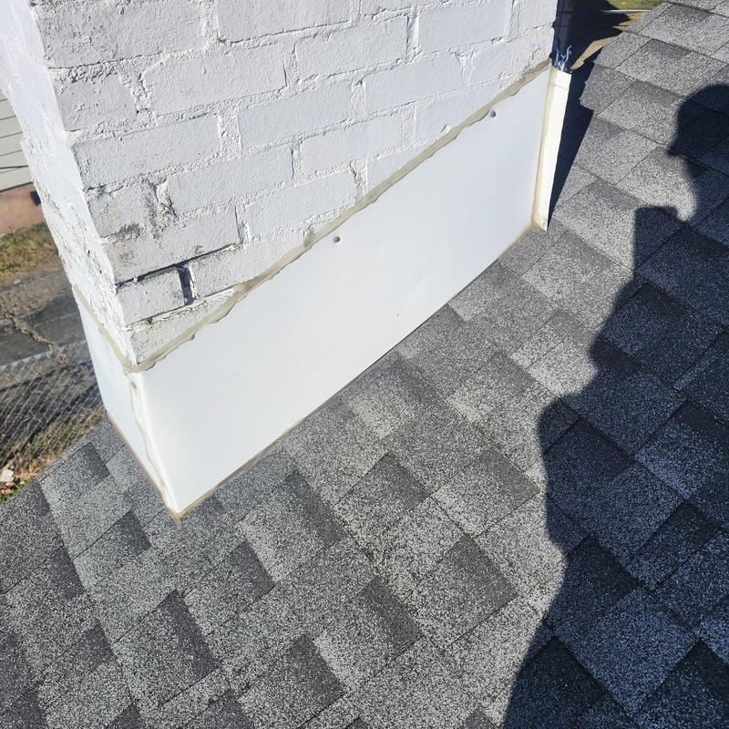 Chimney base metal flashing and roof shingles