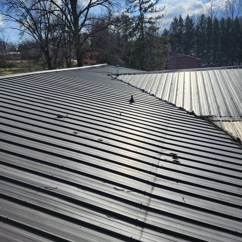 Metal roof panels with visible damage and debris