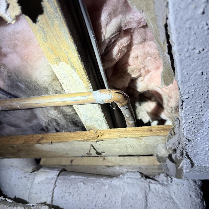 Copper water pipe inside opened wall with insulation and wood framing
