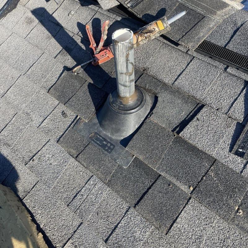 Plumbing pipe boot with roofing tools on asphalt shingles
