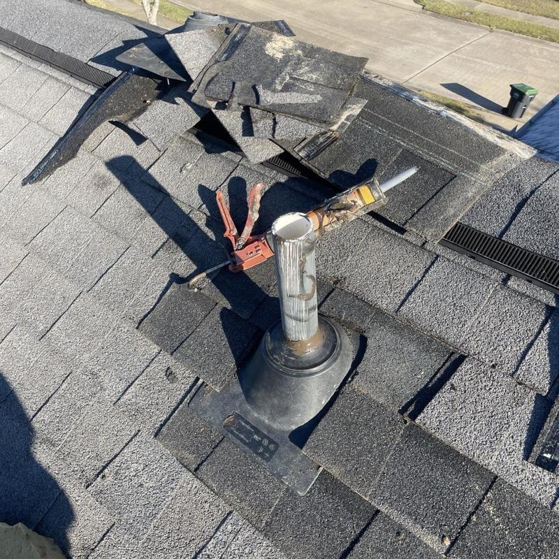 Roof pipe boot with damaged shingles on asphalt roof