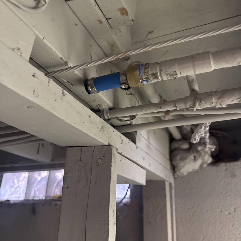 Burst water pipe capped with blue coupling in basement ceiling