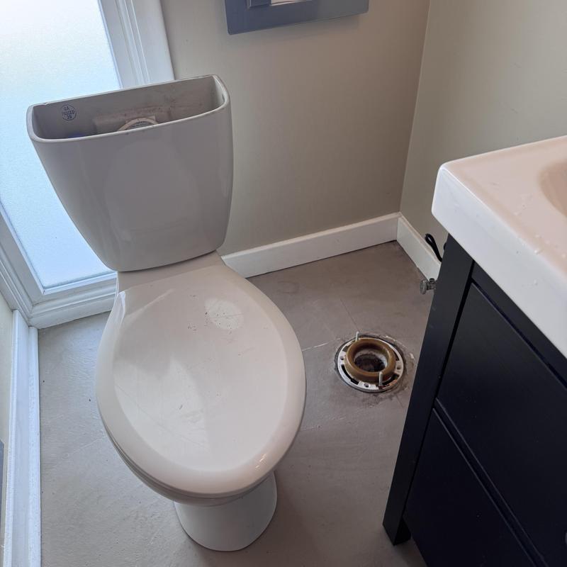 Toilet drain flange exposed next to removed toilet bowl