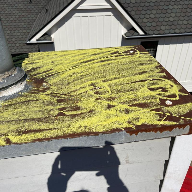 Metal chimney cap with hail damage marked for inspection