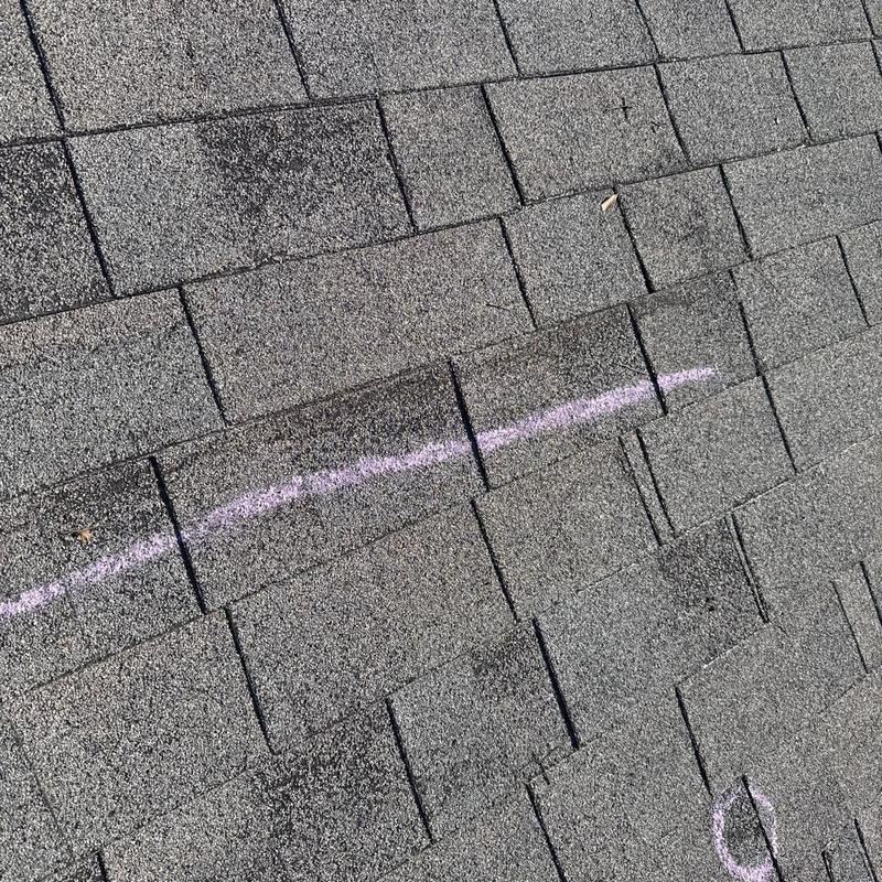 Asphalt shingles with hail damage marked for inspection