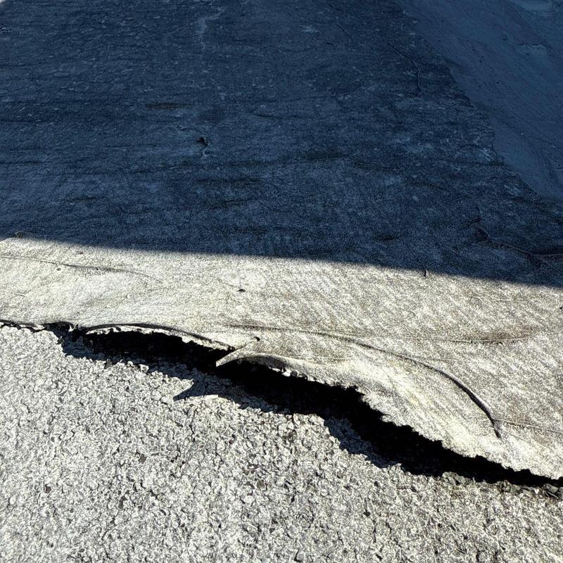 Roofing felt damage with lifted edges and cracking