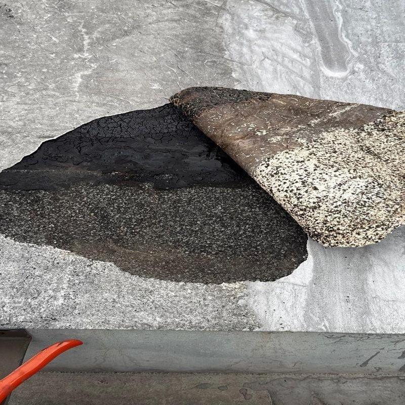 Rolled roofing membrane lift showing underlying layers