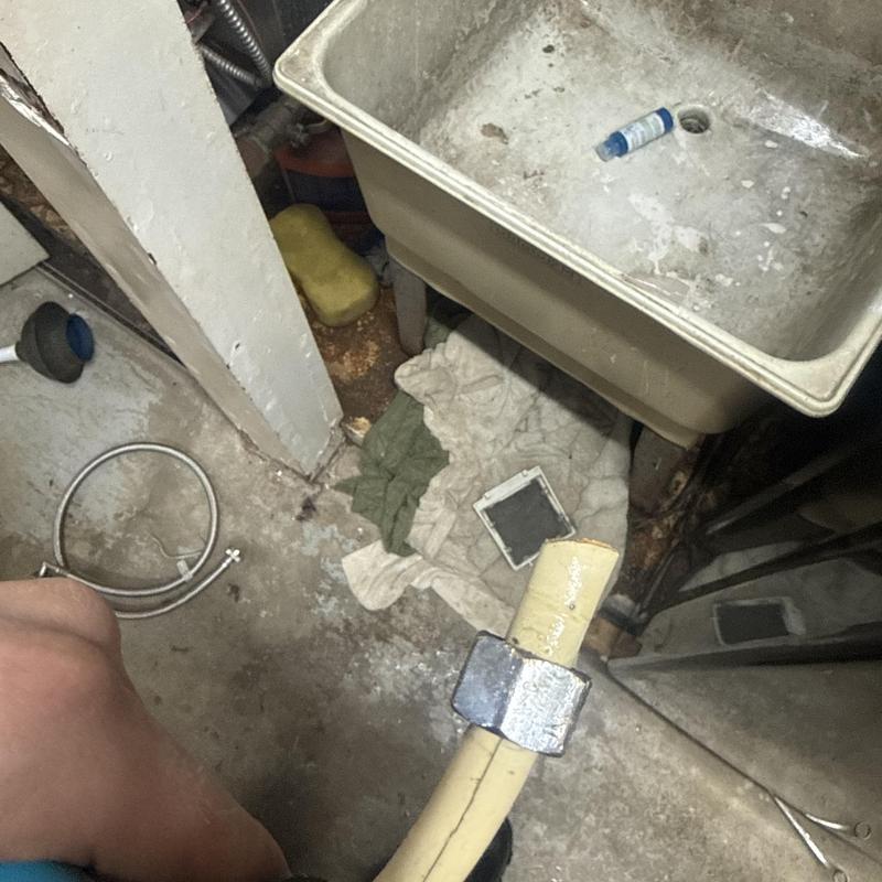 Burst yellow water pipe with metal coupling near utility sink