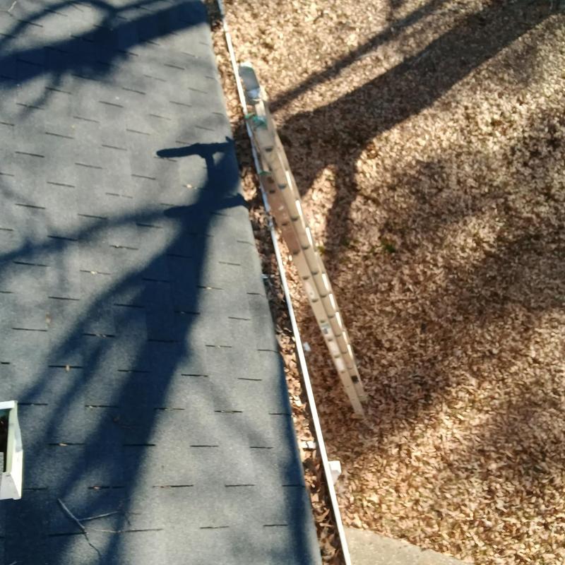 Damaged shingles and debris-filled gutters with ladder nearby