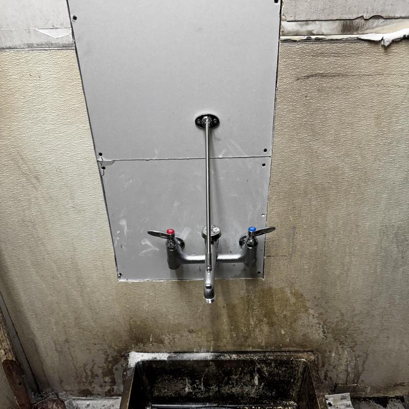 Mop sink faucet with wall-mounted valves and drywall patch