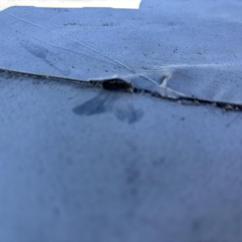 TPO roof membrane puncture and seam damage close-up TPO roof membrane puncture and seam damage close-up
