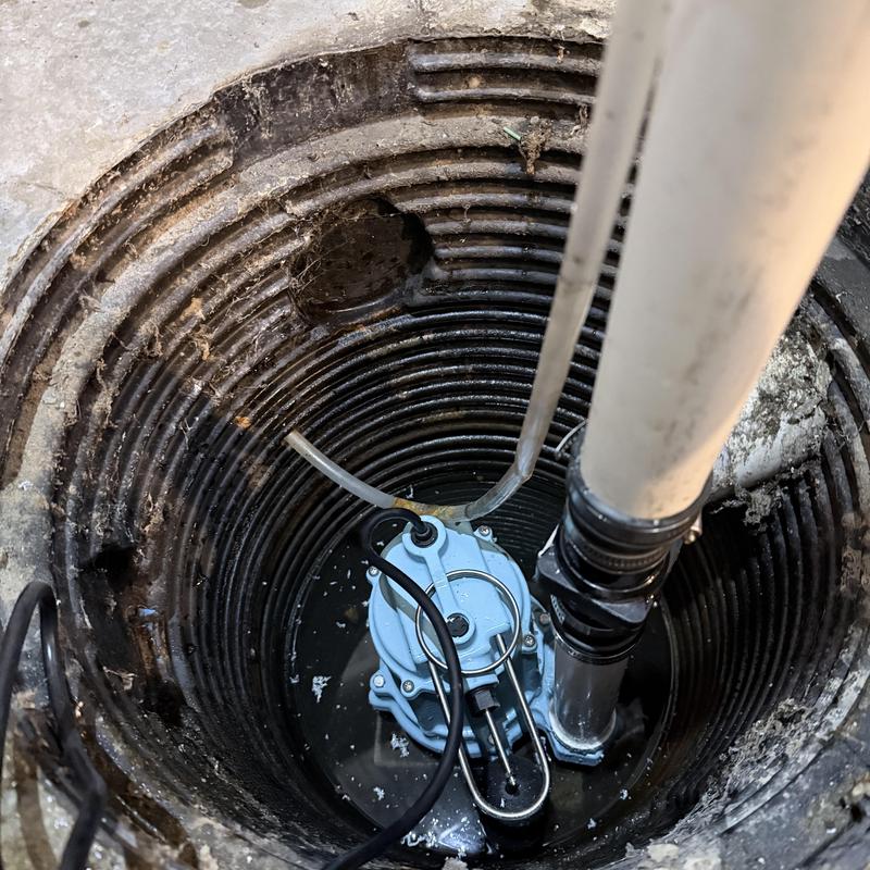 Sump pump system in basement pit with piping and wiring