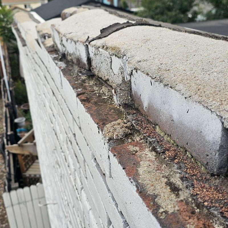 Parapet wall masonry damage and crumbling mortar close-up Parapet wall masonry damage and crumbling mortar close-up