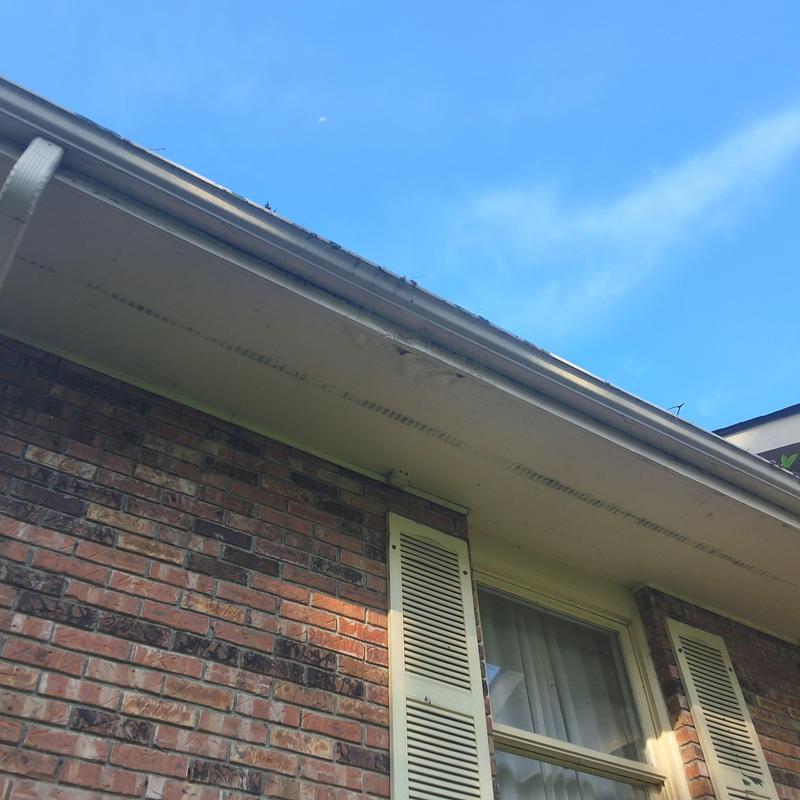 Gutter and fascia on brick house exterior under blue sky