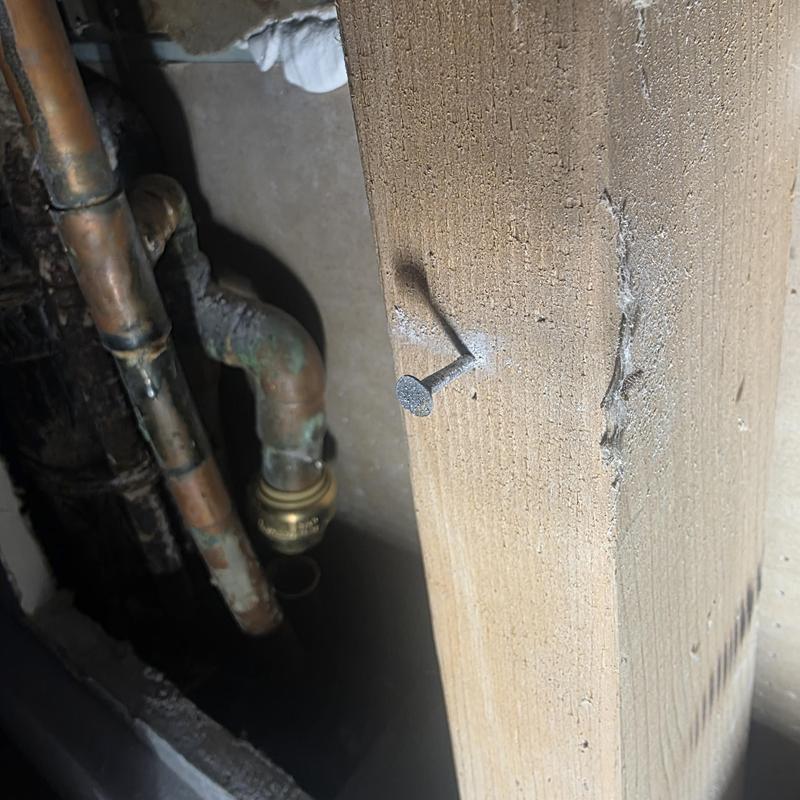 Copper hot water line and manifold near wooden beam