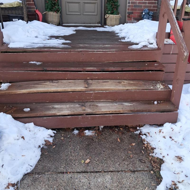 Exterior wooden deck stairs with rotting boards and snow Exterior wooden deck stairs with rotting boards and snow