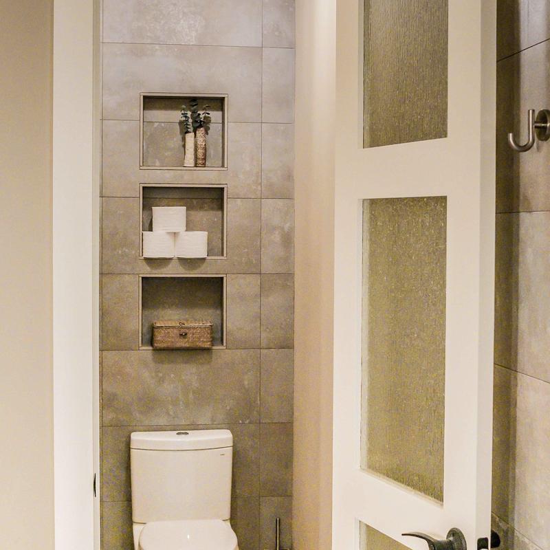 Bathroom tiled storage niches with decor and toilet
