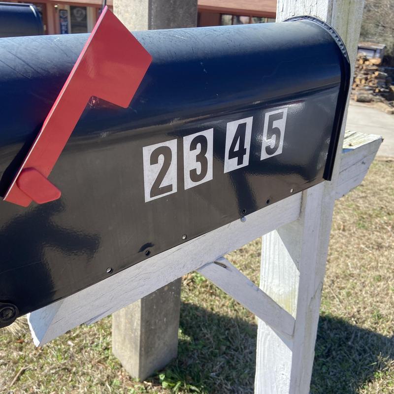 Black metal mailbox with red flag and house numbers Black metal mailbox with red flag and house numbers