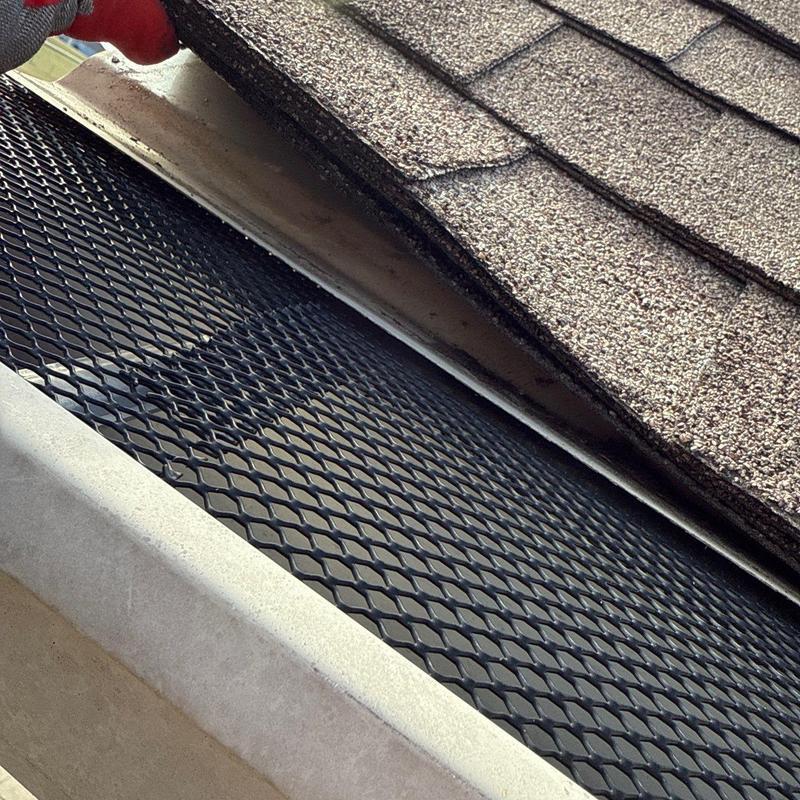 Gutter guard installation beneath asphalt shingles