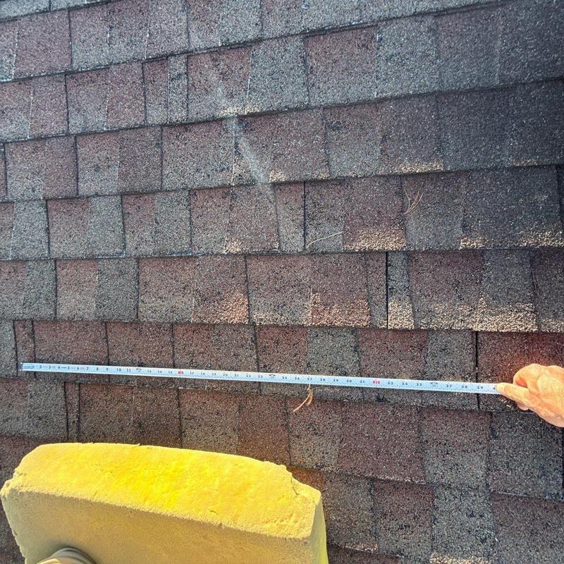 Asphalt shingles with tape measure for damage assessment