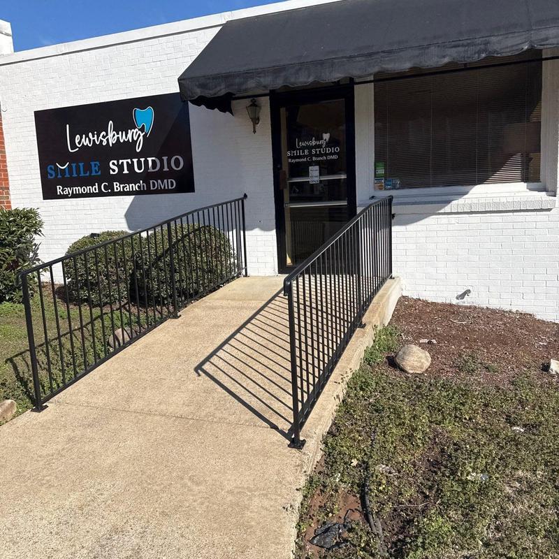 Metal wheelchair ramp railing on concrete walkway outside building