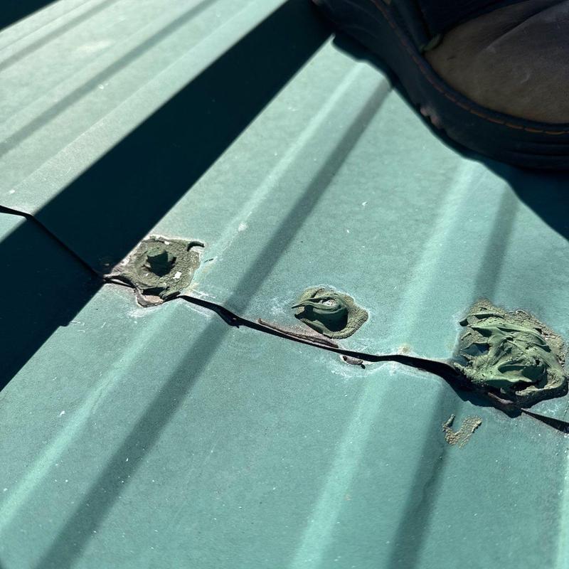 Metal roofing panel crack and sealant deterioration close-up