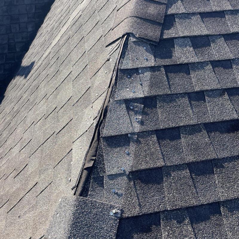 Ridge cap shingles with exposed fasteners on asphalt roof
